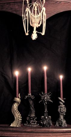 four candles are lit in front of a chandelier on a mantle with black background