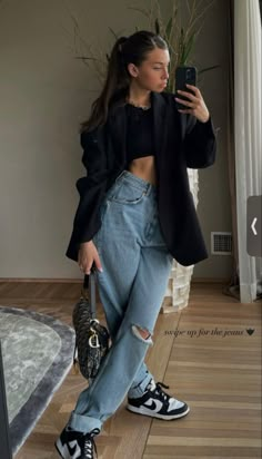 a woman is taking a selfie with her cell phone while wearing ripped jeans and sneakers