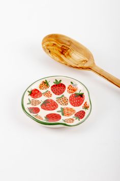 a wooden spoon sitting next to a plate with strawberries on it