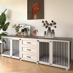 a white sideboard with drawers and vases on top in a room next to a potted plant