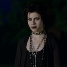 a woman with dark makeup and necklaces on her face is staring at the camera