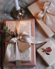 two wrapped presents sitting on top of a table next to a candle