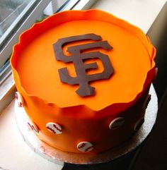 an orange cake with the san francisco giants on it sitting in front of a window