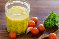 a jar filled with pesto sauce next to tomatoes and parsley