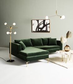 a living room with a large green couch and two lamps on the wall above it