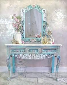 an ornate blue desk with flowers and a mirror