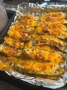 baked stuffed peppers with cheese and other toppings on tin foil lined up on the stove