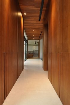 a long hallway with wood paneling and white carpeted flooring on both sides