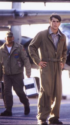 two men standing next to each other in front of an airplane