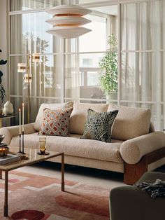 a living room filled with lots of furniture next to a large glass window covered in curtains