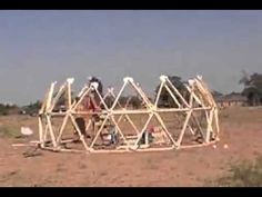 a group of people standing around a structure in the middle of an open field,