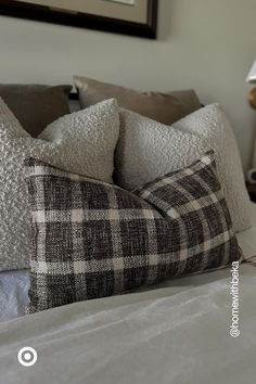 a bed with two pillows on top of it next to a night stand and lamp