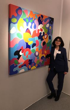 a woman standing next to a large colorful painting