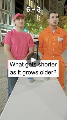 two men in orange and pink shirts standing next to a table with an object on it