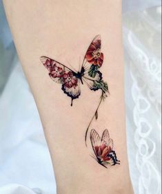 two butterflies with flowers on their wings are shown in this tattoo design by the artist