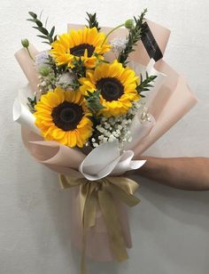 a bouquet of sunflowers is held by someone's hand