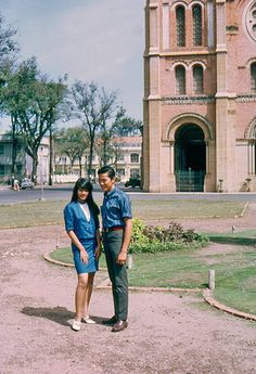 a man and woman standing in front of a large building with a clock on it