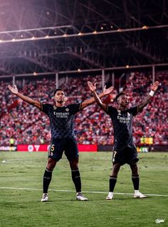 two soccer players standing on the field with their arms in the air