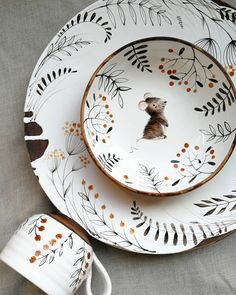 a plate with a mouse on it next to a cup and saucer, which is decorated with leaves