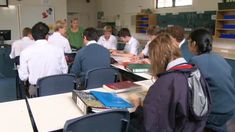 a group of students sitting at desks in a classroom with books on the table