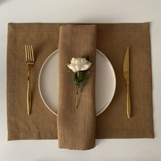 the place setting is ready to be served with gold cutlery and a white rose