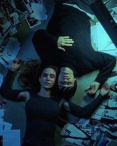 two women are lying on the floor in front of an overhead view of papers and photos