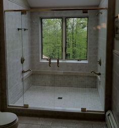 a bathroom with a large glass shower door and window overlooking the trees in the background