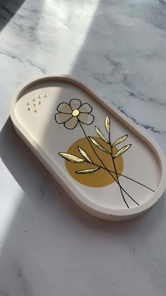 an oval tray with flowers painted on it sitting on a marble countertop next to a window