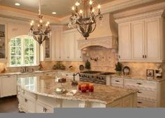 a large kitchen with white cabinets and marble counter tops, chandelier hanging from the ceiling