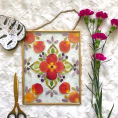 an art work with flowers and scissors on a white surface next to a pair of gloves