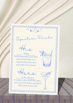 a blue and white menu card with a cocktail glass on the front, sitting on top of a wooden table