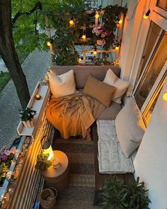 an overhead view of a balcony with lights and pillows on the couch, potted plants