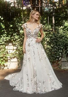 a woman in a wedding dress standing next to a wall with ivy growing on it