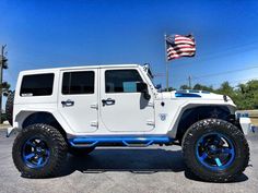 a white jeep parked in a parking lot with an american flag on the side of it