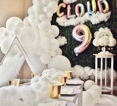 a party with balloons, clouds and other decorations on the wall in front of it