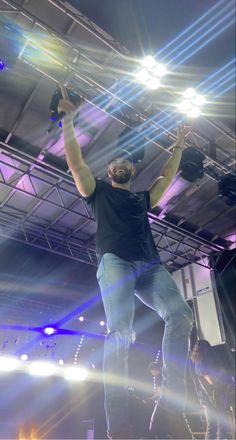 a man standing on top of a stage with his arms in the air and hands raised