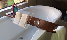 an open book and two glasses sit on the edge of a bathtub next to a window