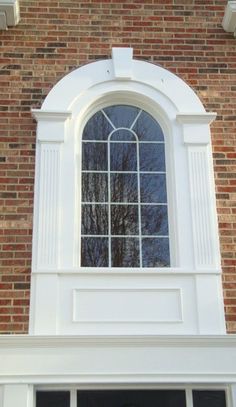 an open window on the side of a brick building with white trim and black shutters