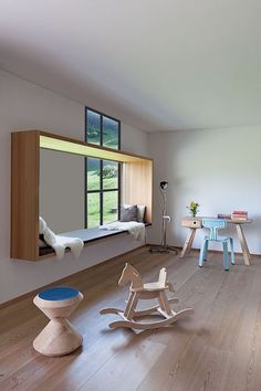 a child's room with wooden furniture and large window overlooking a green field in the distance