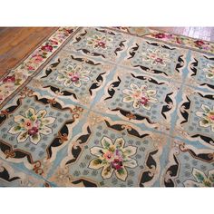 a blue and white rug with flowers on the ground in front of a wooden floor