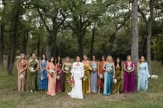 a group of women standing next to each other in front of some trees and grass