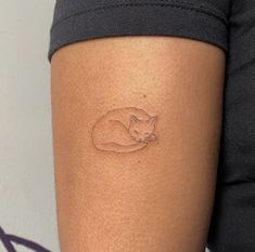 a woman's arm with a small cat tattoo on the back of her leg