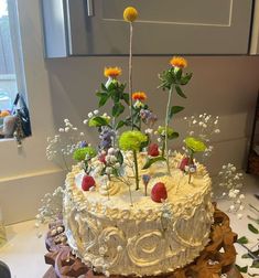 a cake decorated with flowers and fruit on a table