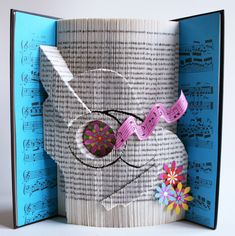 an open book that has some paper on it and is decorated with music notes, flowers, and buttons