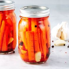 two mason jars filled with pickled carrots and garlic