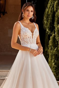 a woman in a wedding dress posing for the camera with her hand on her hip