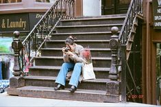 a woman sitting on the steps looking at her cell phone