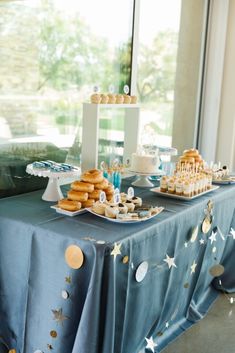 a table topped with donuts and pastries on top of a blue table cloth