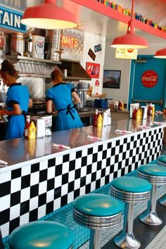 the interior of a fast food restaurant with blue stools and black and white checkered counter