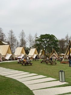 people are sitting at picnic tables in front of teepees and tent like structures